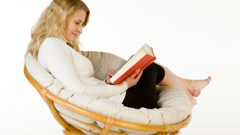 Junge Frau im runden Sesselstuhl beim Lesen