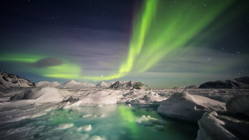 Grünes Polarlicht über Winterlandschaft in Spitzbergen, Norwegen