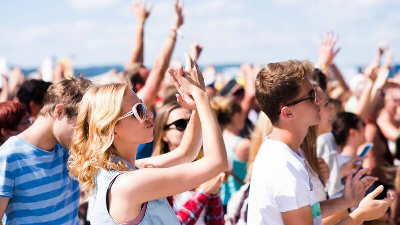 Jugendliche Crowd feiert bei einem sommerlichen Open-Air-Musikfestival