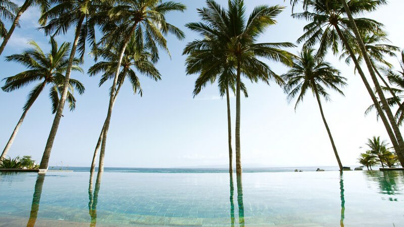 Resort Swimming Pool mit Palmen unter blauem Himmel