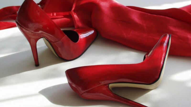 Rote Lack-High Heels, daneben rotes Satinkleid