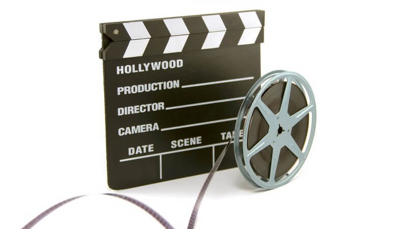 Filmklappe und Filmrolle auf weißem Hintergrund
