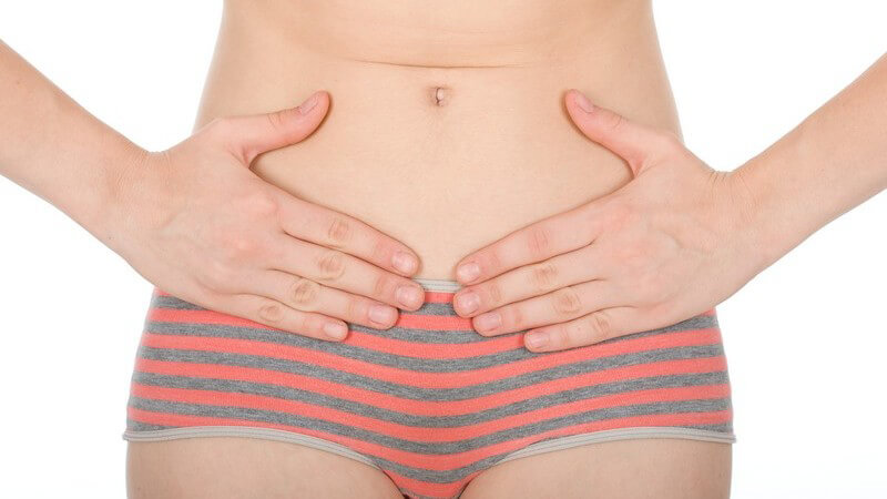 Frau hält Hände auf ihren nackten Bauch, Schmerzen, Menstruation, Periode