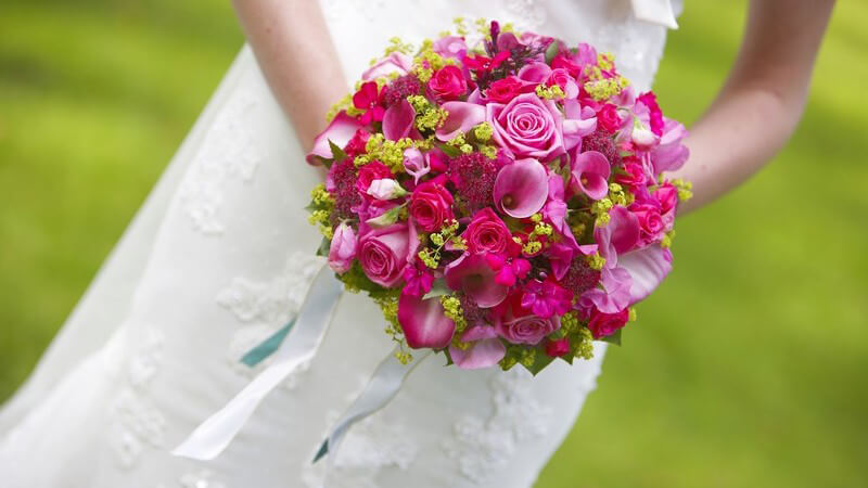 Rosa-pinker Rosenstrauß einer Braut, sie hält ihn in Händen