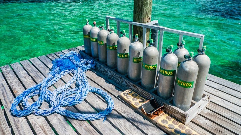 Mehrere Nitrox-Tauchflaschen stehen auf einem Steg am grünen Wasser