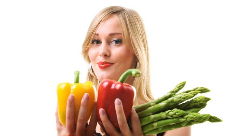 Junge Frau mit frischer Paprika, Tomaten, grünem Spargel, weißer Hintergrund