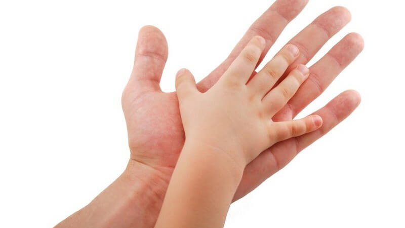 Babyhand berührt Handfläche einer Männerhand