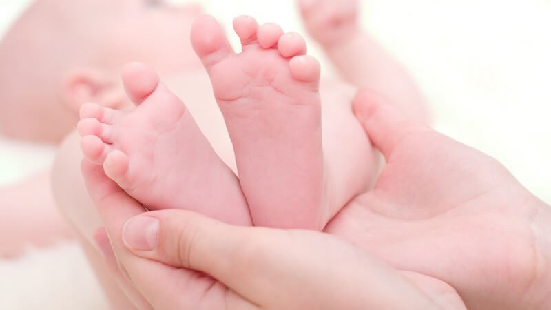 Mutter hält Füße ihres Neugeborenen