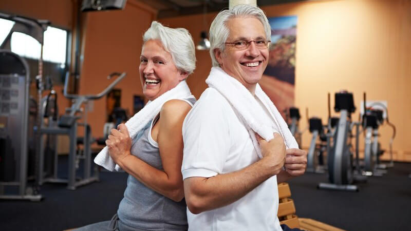 Älteres Paar mit weißen Handtüchern über den Schultern im Fitness-Studio