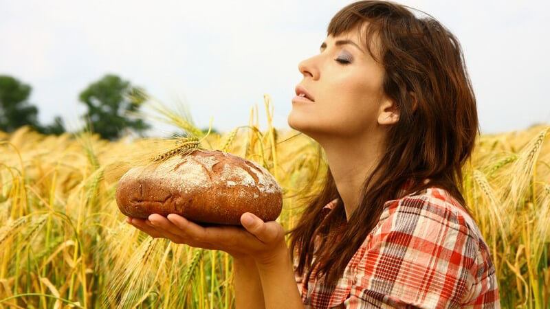 Frau im Feld riecht an frisch gebackenem Brot