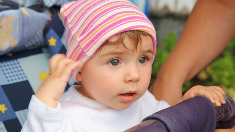 Baby mit rosa Mütze im Kinderwagen