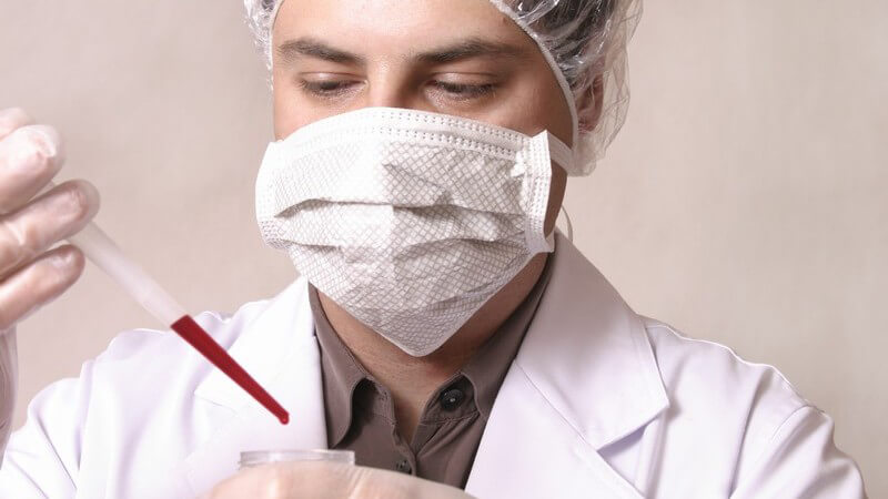 Untersuchung - Chemiker mit Mundschutz bei einer Blutuntersuchung
