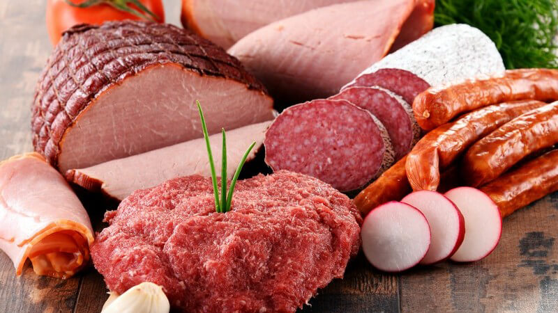 Diverse Fleischprodukte auf Holztisch - Hackfleisch, Würste und Aufschnitt