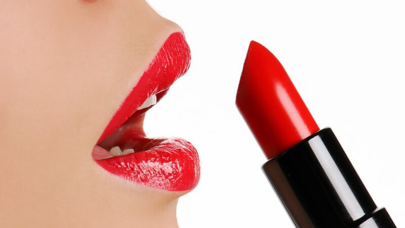 Roter Mund einer Frau im Profil, daneben ein roter Lippenstift in schwarzem Schaft