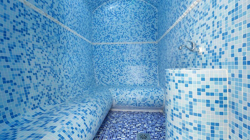 Blick in ein leeres Dampfbad, komplett aus kleinen blauen Mosaikfliesen