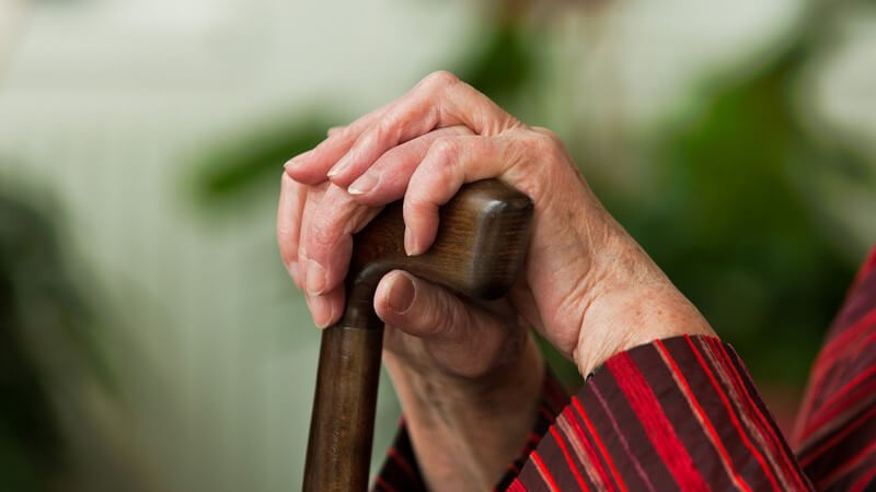 Nahaufnahme Hände alter Frau auf Gehstock gestützt