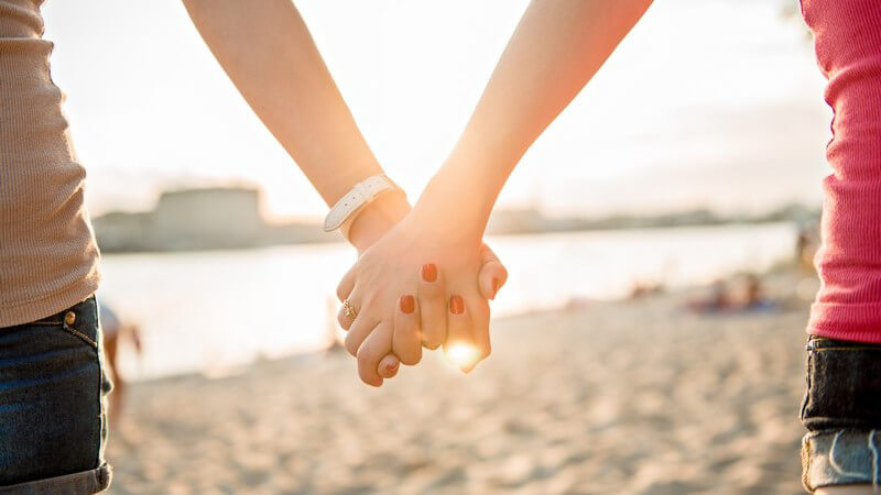 Händchenhaltende Frauen am Strand