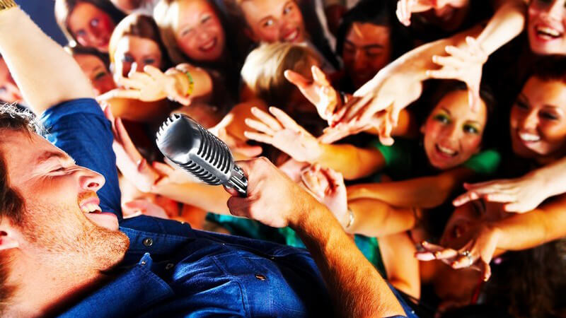Sänger am Mikrofon wird von Mädchen in Menschenmenge bejubelt