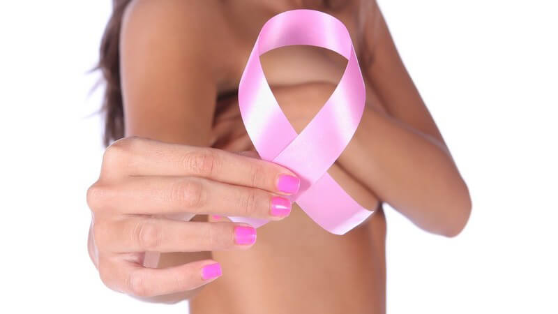 Rosane Brustkrebs-Schleife wird in Kamera gehalten von Frau mit nacktem Oberkörper
