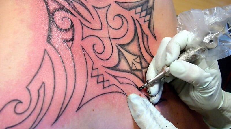 Nahaufnahme Tätowierer bei der Arbeit, macht Tattoo auf Rücken