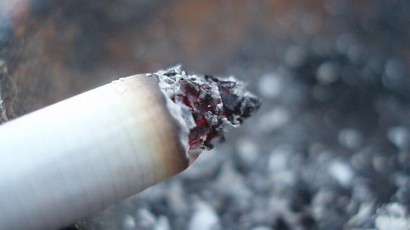 Nahaufnahme glimmende Zigarette über Aschenbecher