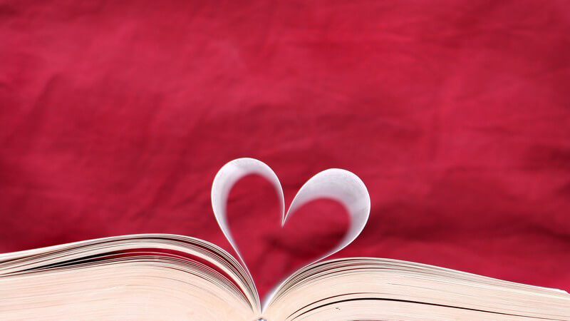 Aufgeschlagenes Buch, Seiten in Herzform, roter Hintergrund