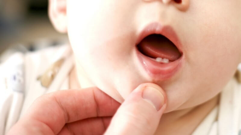 Nahaufnahme Vaterhand zeigt Babys erste Zähne