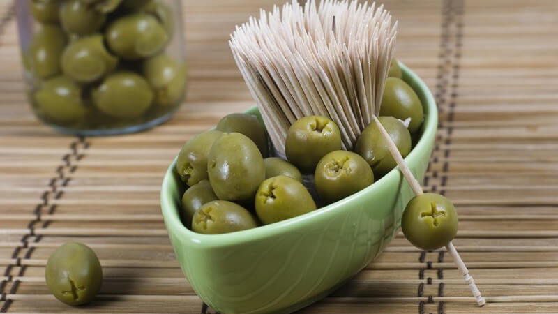 Grüne Oliven in Schale mit Zahnstochern