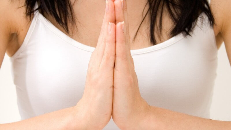 Frau mit gefalteten Händen beim Yoga oder Meditieren