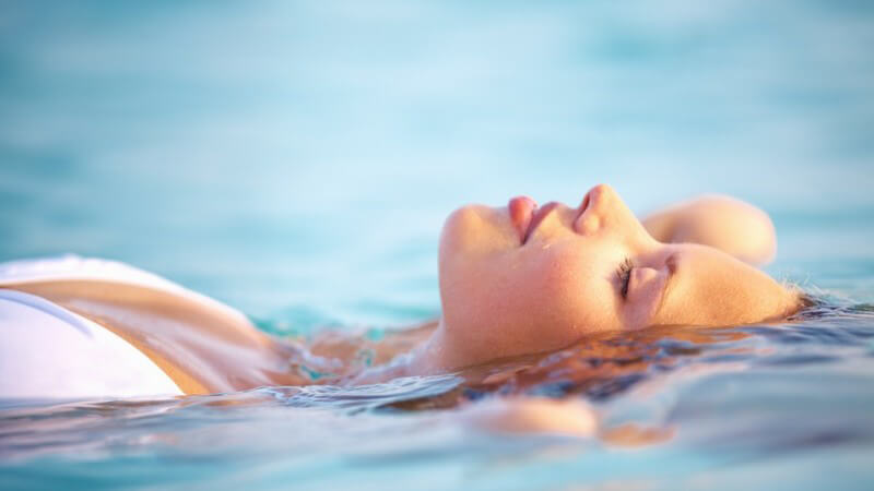 Frau liegt entspannt auf dem Rücken im Wasser