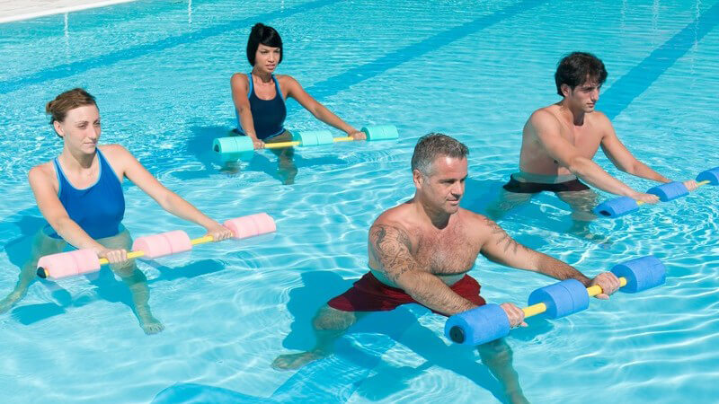 Wassergymnastik: Männer und Frauen mit Hanteln im Schwimmbecken