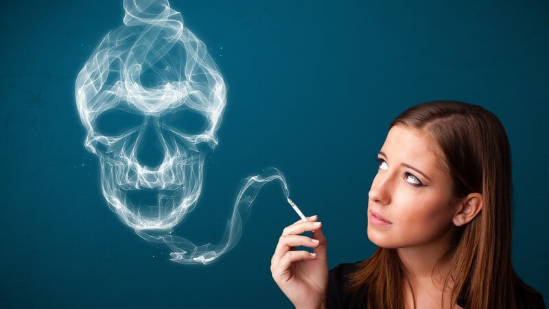 Zigarette rauchende Frau blickt zu einer Dunstwolke in Totenkopfform