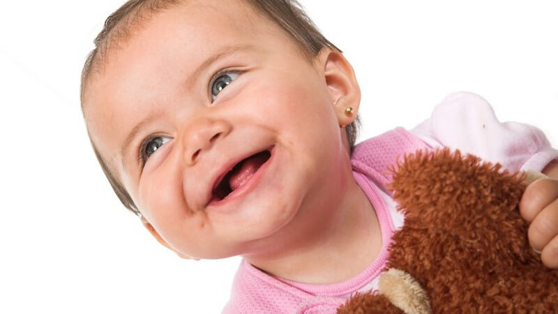 Baby Mädchen mit Teddybär lächelt, schaut nach oben