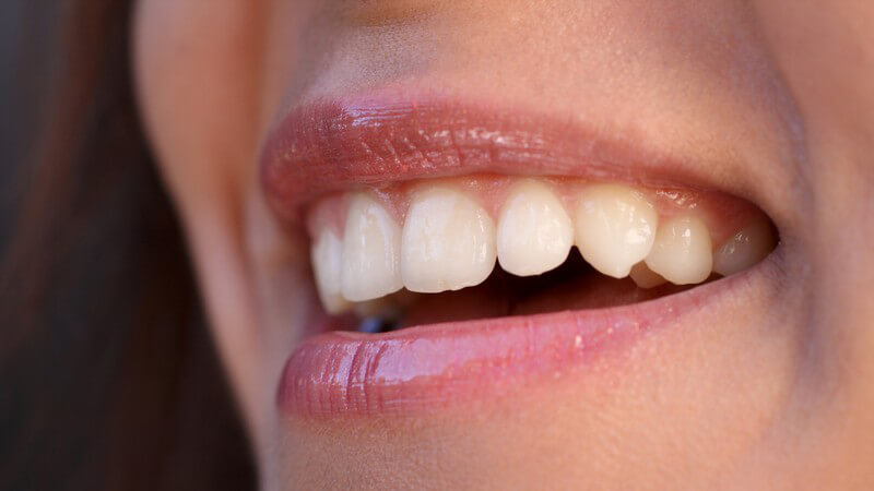 Lachender Mund einer Frau, gesunde Zähne, Lipgloss auf Lippen