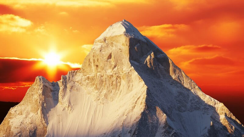 Himalaya Gebirge, dahinter orange-roter Himmel im Sonnenuntergang