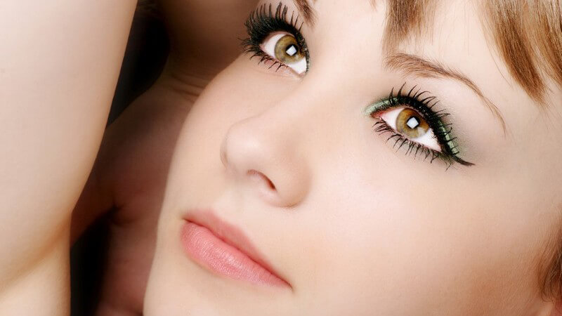 Gesicht einer jungen Frau mit betonten, geschminkten, braunen Augen