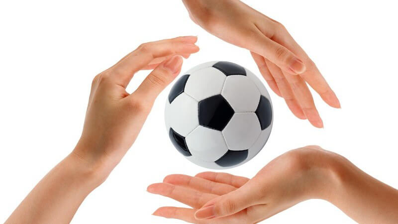 Drei Frauenhände um kleinen Fußball