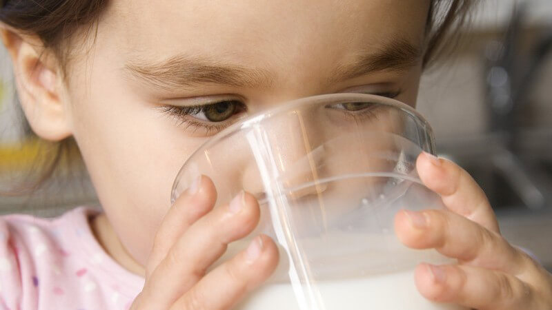 Kleines Mädchen trinkt Milch aus Glas