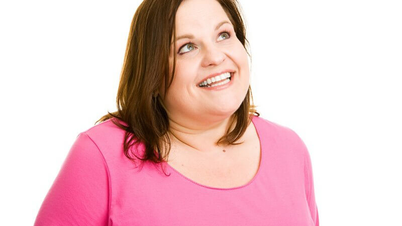 Dicke Frau in pinkem Oberteil blickt nach oben und lächelt