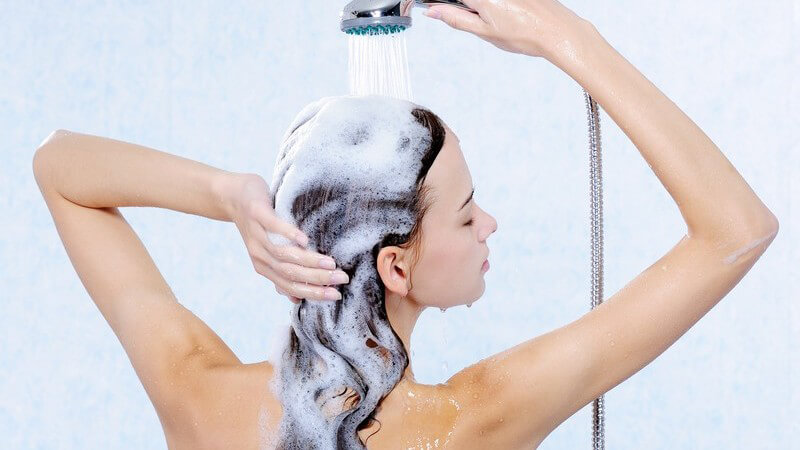 Rückansicht Frau wäscht sich lange Haare unter der Dusche