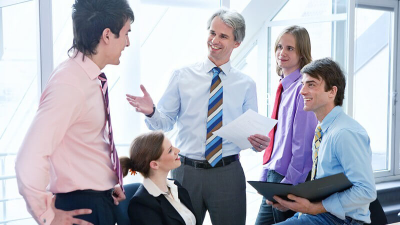 Kleine Gruppe im Businesslook bei lockerem Meeting im Büro