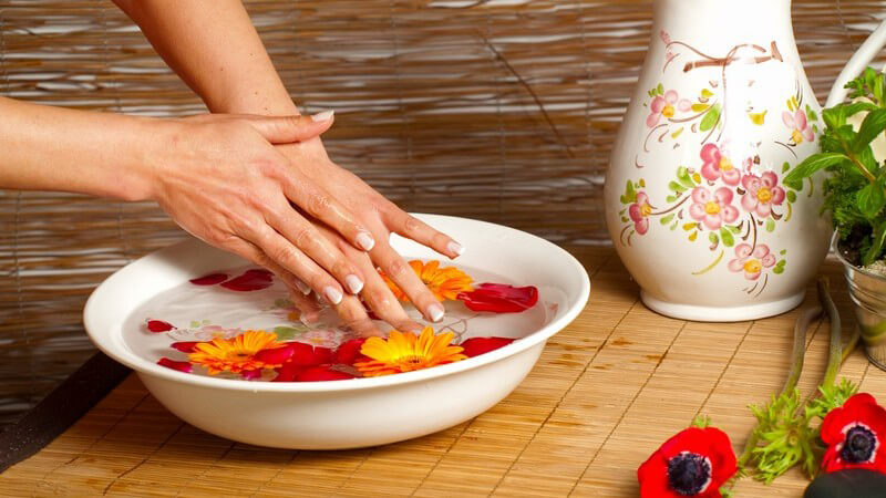 Frau wäscht Hände im Blütenbad