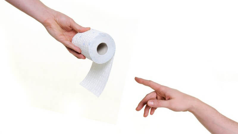 Eine Hand reicht der anderen Rolle Toilettenpapier auf weißem Hintergrund