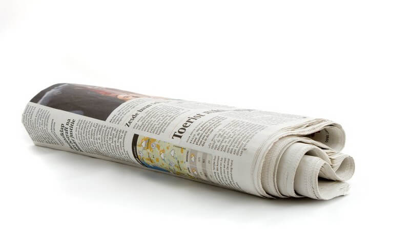 Zusammengerollte, niederländische Zeitung auf weißem Hintergrund