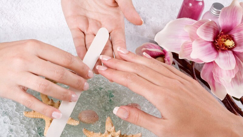 Frau bei Maniküre, Nägel der rechten Hand werden mit Nagelfeile gefeilt