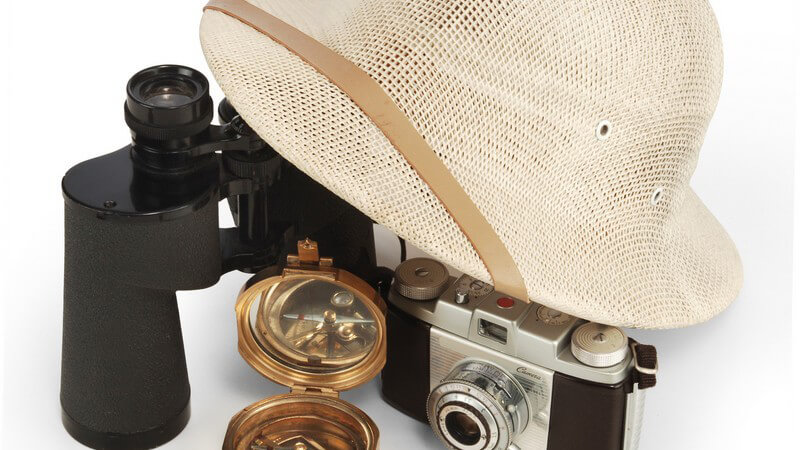 Safarihut, Kompass, Fernglas, Fotoapparat auf weißem Hintergrund