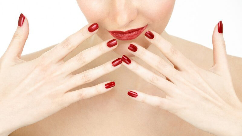 Ausschnitt Frau mit rot geschminkten Lippen und roten Fingernägeln