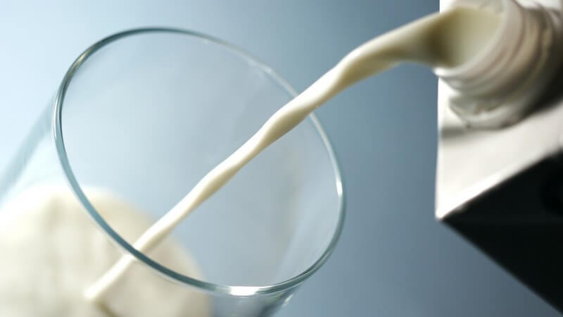Milch fließt von einer Milchtüte ins Glas