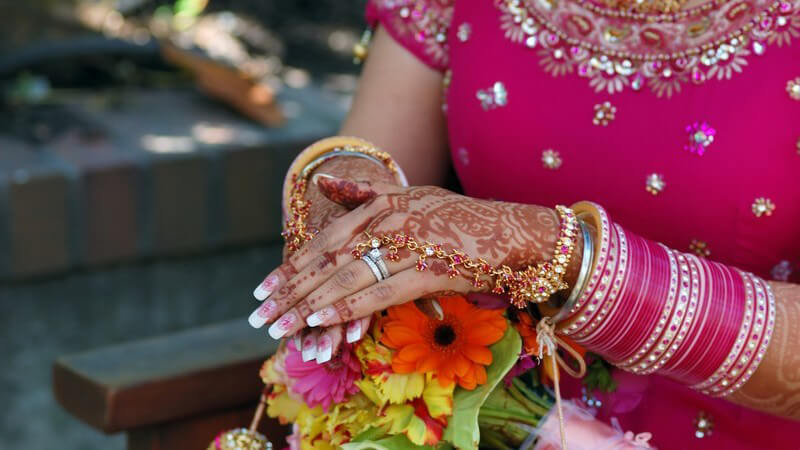 Oberkörper ohne Kopf einer indischen Frau in pink, Hände mit Henna bemalt, viele Armreifen
