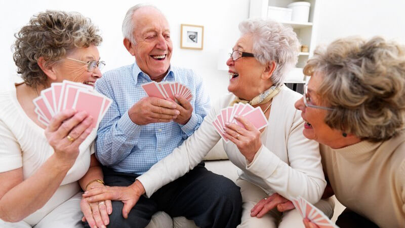 Gruppe alter Menschen beim Kartenspiel, alle lachen